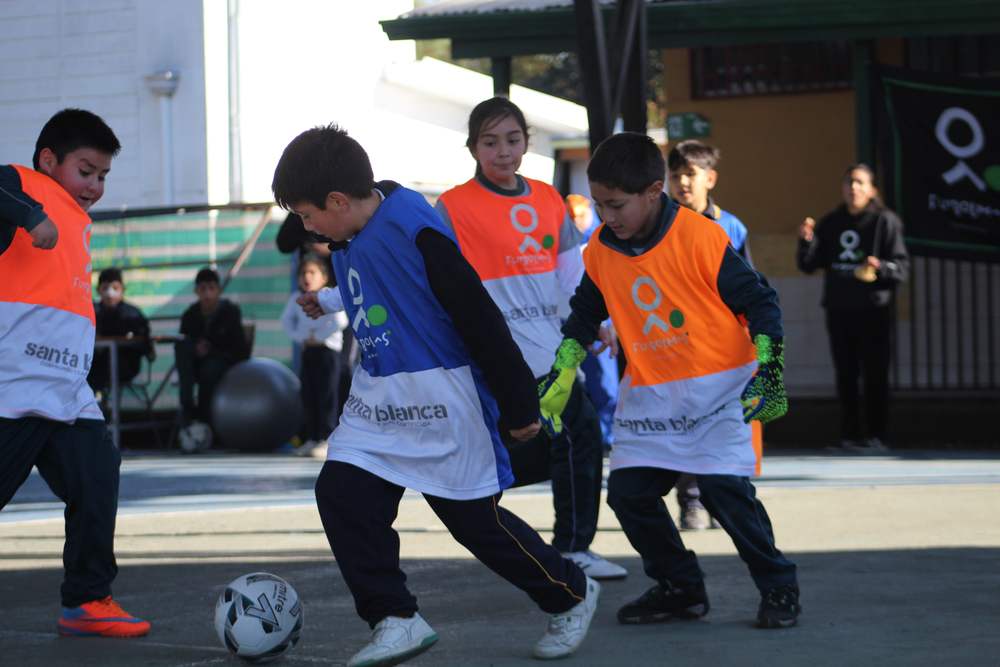 Niñas y niños jugando con petos de Fútbol Más y Santa Blanca